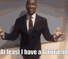a man in a suit and tie is saying that at least he has a girlfriend .