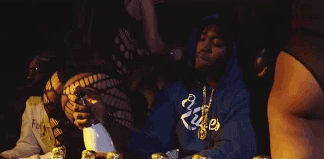 a man in a blue hoodie is sitting at a table with a woman in a black dress .