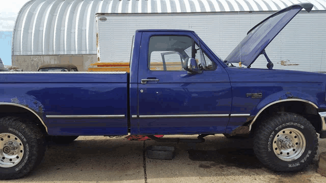a blue ford f150 truck is parked with its hood up