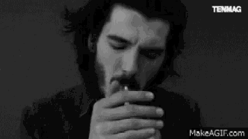 a black and white photo of a man lighting a cigarette with the words tenmag on the bottom right