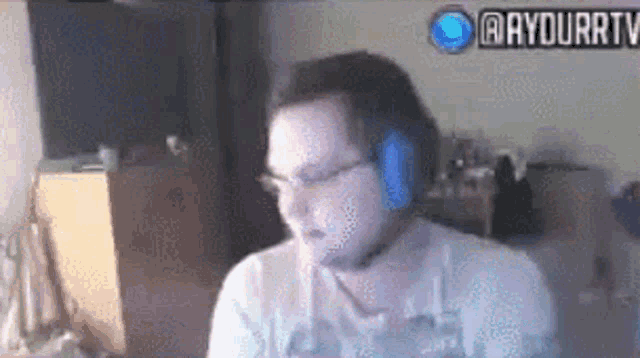 a man wearing headphones and glasses is sitting in front of a computer screen .