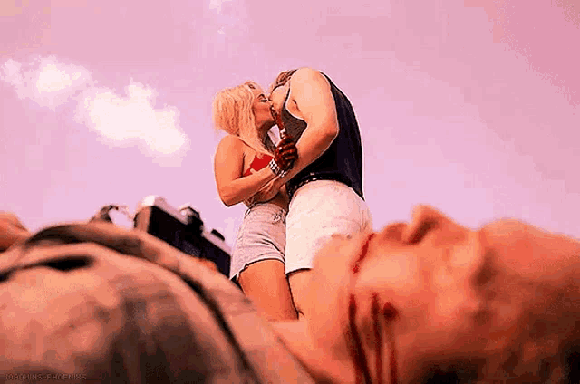 a man and a woman are kissing in front of a dead body .