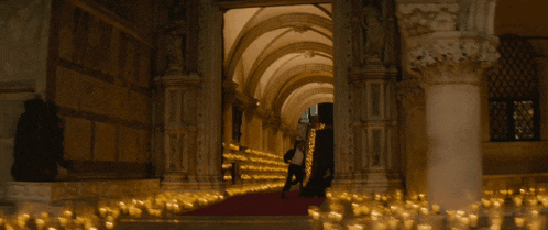 a very long hallway with a red carpet and lots of candles