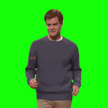 a man in a blue sweater holds his hands up in the air