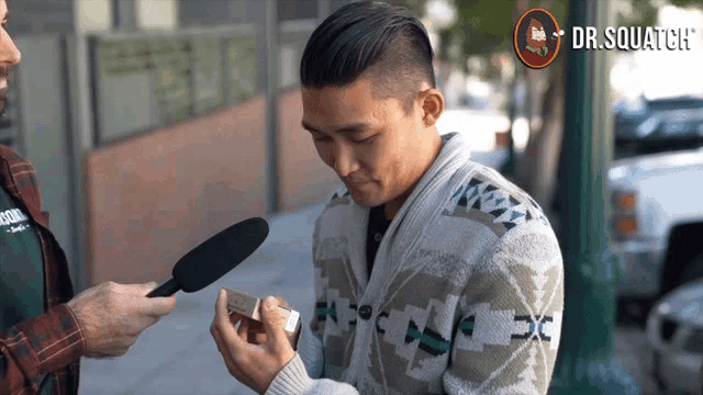 a man wearing a sweater is being interviewed by a man with a microphone and the words dr squatch on the bottom