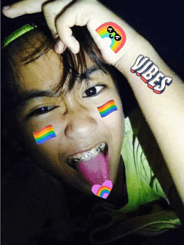 a girl with rainbows on her face and the word vibes on her arm