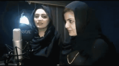 two women singing into a rode microphone while wearing hijabs