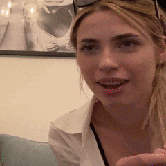 a woman in a white shirt is smiling in front of a picture