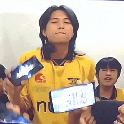 a man in a yellow shirt with the word n on it holds a cell phone