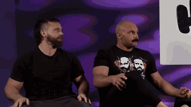 two men sitting next to each other with one wearing a t-shirt that says ' brothers ' on it