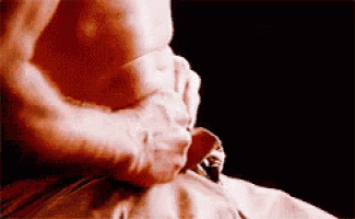 a man without a shirt is holding his stomach in his hands .