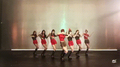 a group of women are dancing on a stage with the word ec on the bottom right