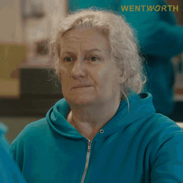 a woman in a blue sweatshirt with the word wentworth on the bottom right