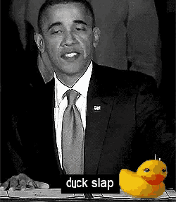 a black and white photo of barack obama with a rubber duck behind him that says duck slap