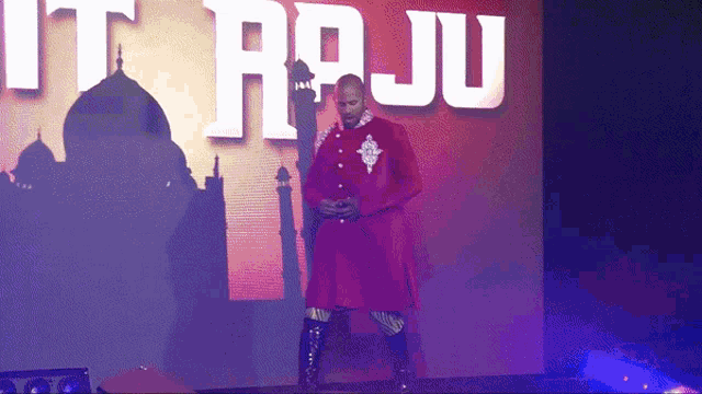 a man in a red coat is standing in front of a screen that says " it raju "