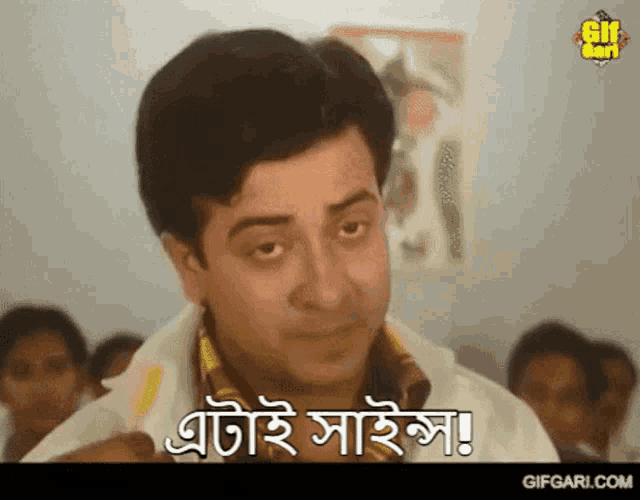 a man is making a funny face in front of a group of people and says " gifgari.com " at the bottom