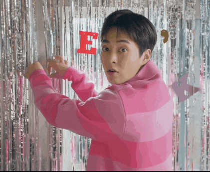 a man in a pink striped shirt is standing in front of a silver curtain
