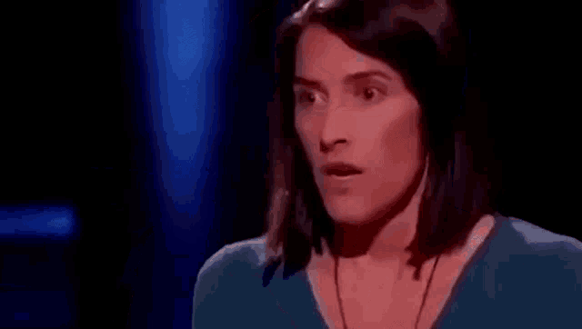 a woman in a blue shirt is making a surprised face on a television show .