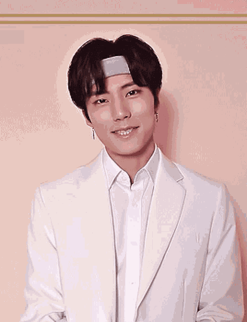 a young man wearing a headband and a white jacket looks at the camera