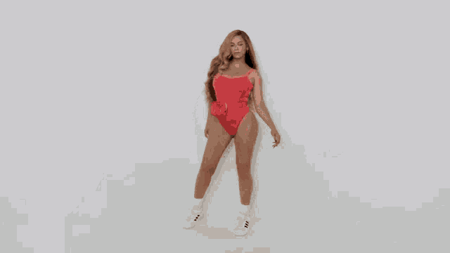 a woman in a red swimsuit and white sneakers is dancing .