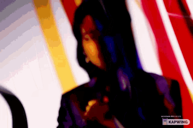 a woman in a hooded jacket is standing in front of a colorful background