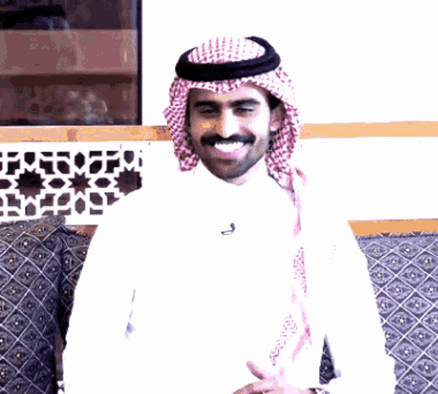 a man wearing a head scarf and a white shirt has the letter j on his shirt