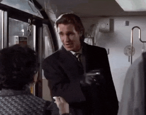 a man in a suit and tie talking to a woman on a bus