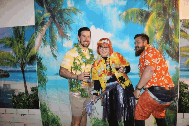 two men and a woman pose for a photo in front of a beach scene