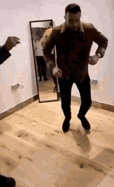a man with a beard is dancing in a room with a mirror .
