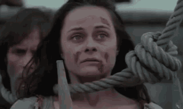 a woman with blood on her face is tied to a rope and says " likt blommer vaxer hon upp och vissnar bort "