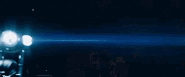 a motorcycle is driving down a dark street at night with its headlights on .
