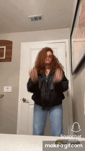 a woman in a leather jacket and jeans is dancing in front of a door
