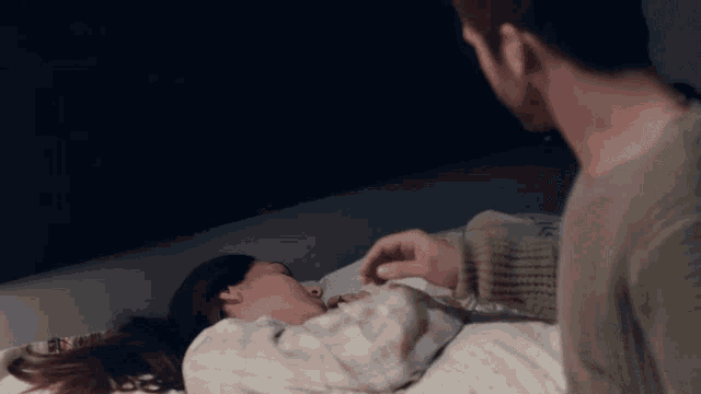 a man is standing next to a woman in bed