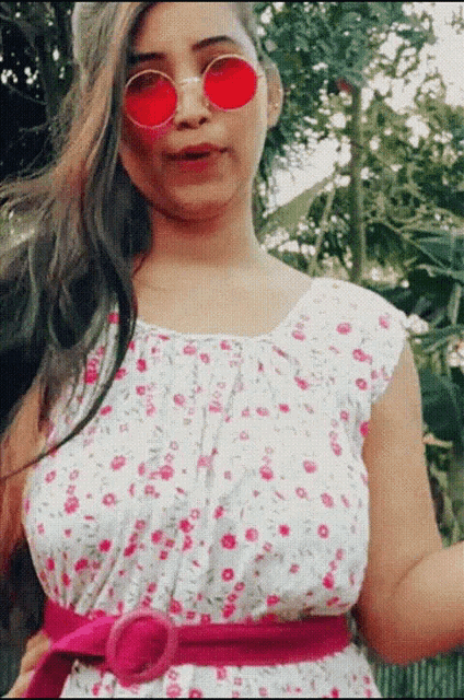 a woman in a floral dress and red sunglasses