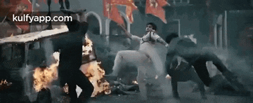 a group of people are standing around a burning building .