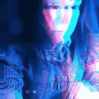 a woman in a plaid shirt is standing in front of a blue and pink light .