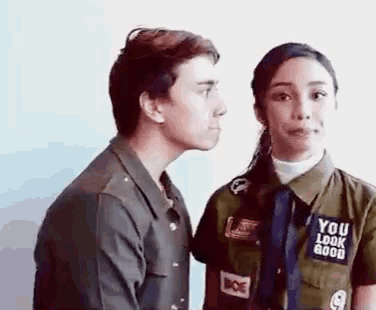 a man is whispering into a woman 's ear while standing next to her .