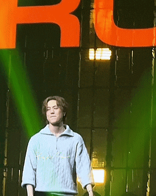 a man stands on a stage in front of a large orange letter r