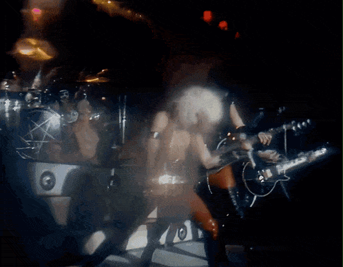 a blurred image of a band on stage with a pentagram in the background