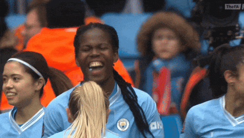 a group of female soccer players are laughing and one of them is wearing a jersey that says city