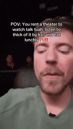 a man in a green shirt is talking to someone in a theater