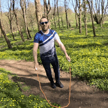 a man wearing sunglasses is jumping a jump rope in a field of yellow flowers