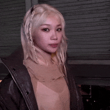 a woman with blonde hair is wearing a leather jacket and a sheer top
