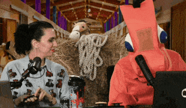 a man in a fox costume talks to a woman in front of a hay bale with a sign that says ranch