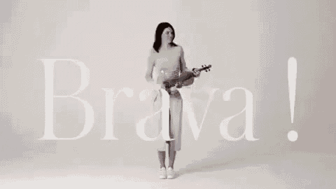 a woman in a white dress is standing in front of a sign that says brava .