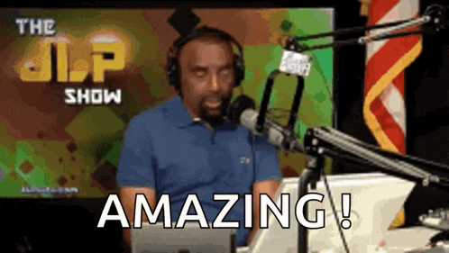 a man in a blue shirt is sitting in front of a microphone and says amazing