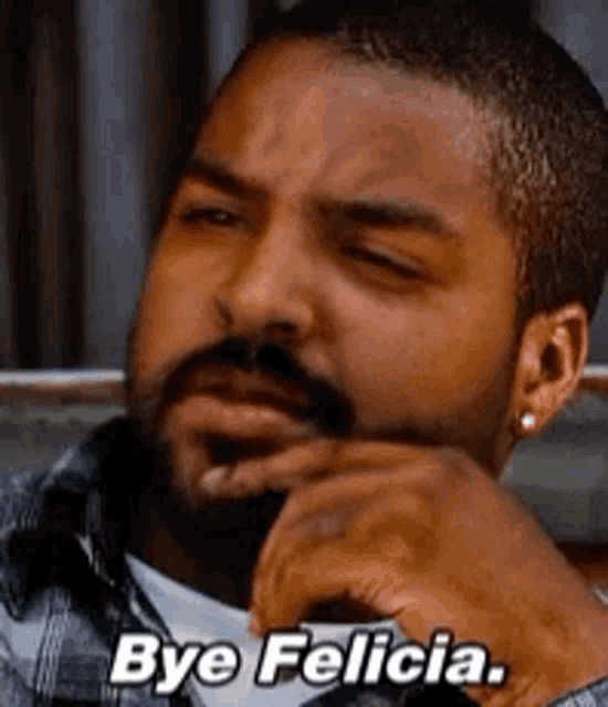 a man with a beard is sitting on a couch with his hand on his chin and says `` bye felicia '' .