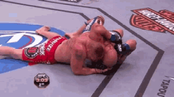 two men are wrestling in a ring and one of them is wearing a red short that says ' ufc '