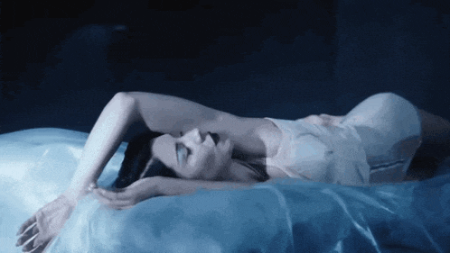 a woman in a white dress is laying on a bed