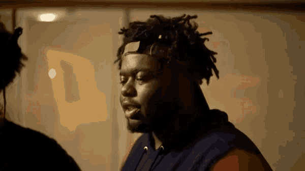 a man with dreadlocks is wearing a headband and a blue hoodie .
